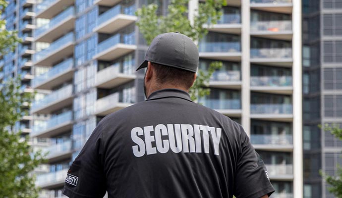 A back-view of a apartment complex security guard wearing a black shirt labeled SECURITY