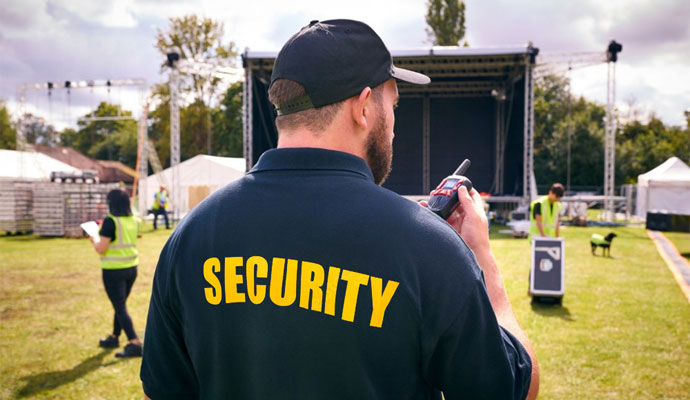 Security guard monitoring outdoor event venue with communication radio