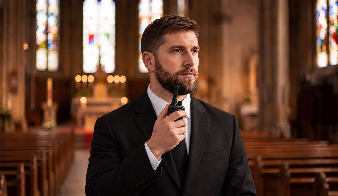 Professional security officer with handheld radio inside place of worship