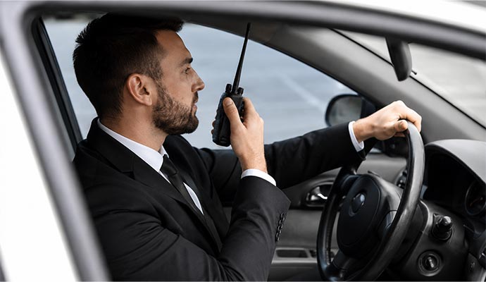 Security guard with walkie-talkie in a car