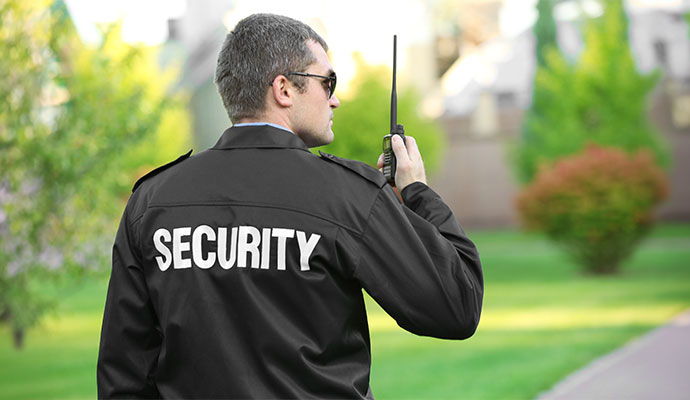 Professional security guard with radio patrolling outdoors