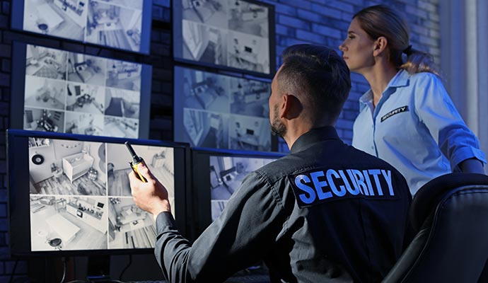 Security control room with personnel monitoring surveillance screens