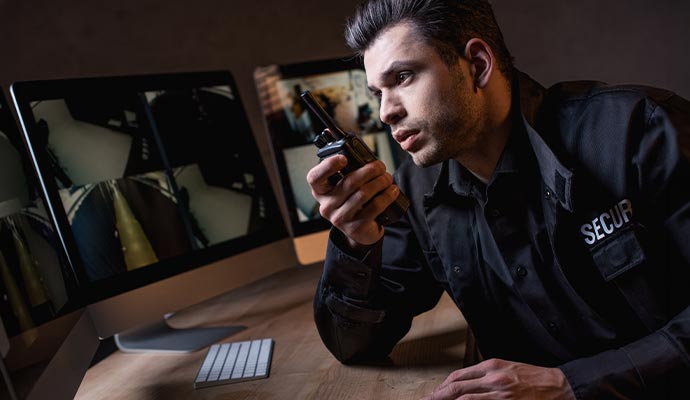 Security guard monitoring surveillance camera using walkie talkie