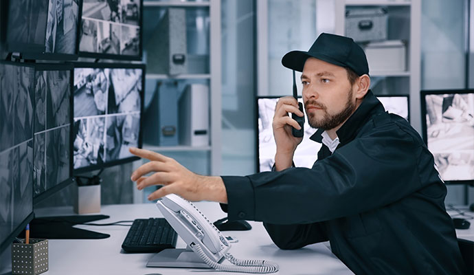 Security guard monitoring surveillance cameras in control room