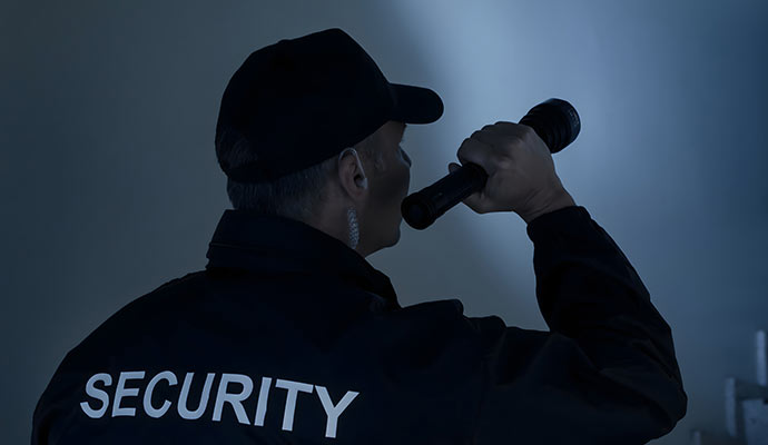 Security guard patrolling at night with flashlight