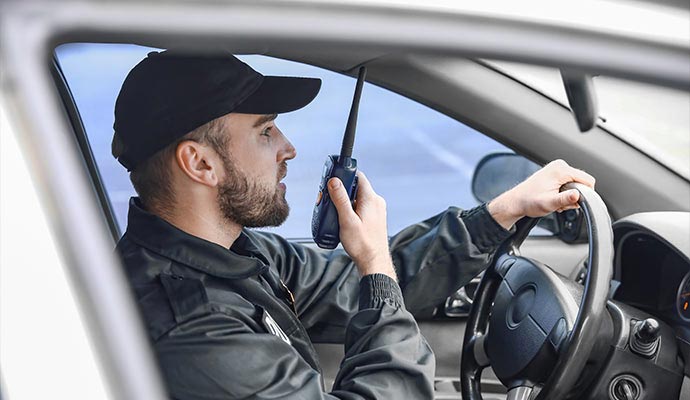 Security guard patrolling in car using walkie talkie