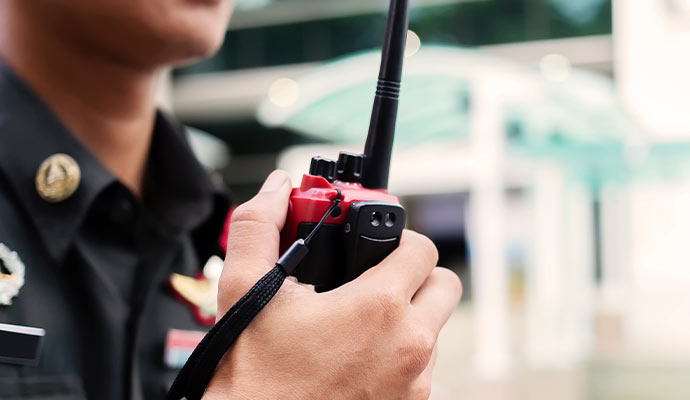 Security person holding red walkie talkie radio