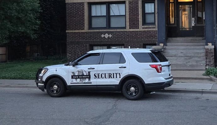 An M&M Security vehicle in front of a residential building