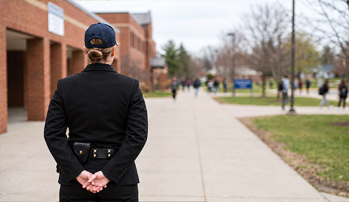 Standing security guard monitoring school campus walkway and students