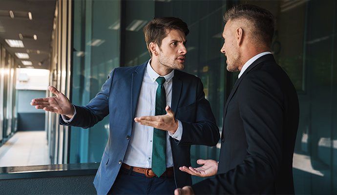 Two individuals engaged in a heated workplace disagreement in an office hallway